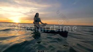 一个女人在海洋中的桨板上休息，冥想。 4K.